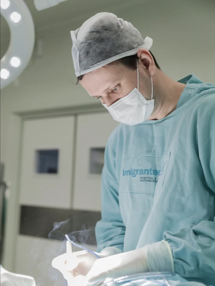 O Dr. Leonardo Jacobsen operando, paramentado, sob o foco cirúrgico