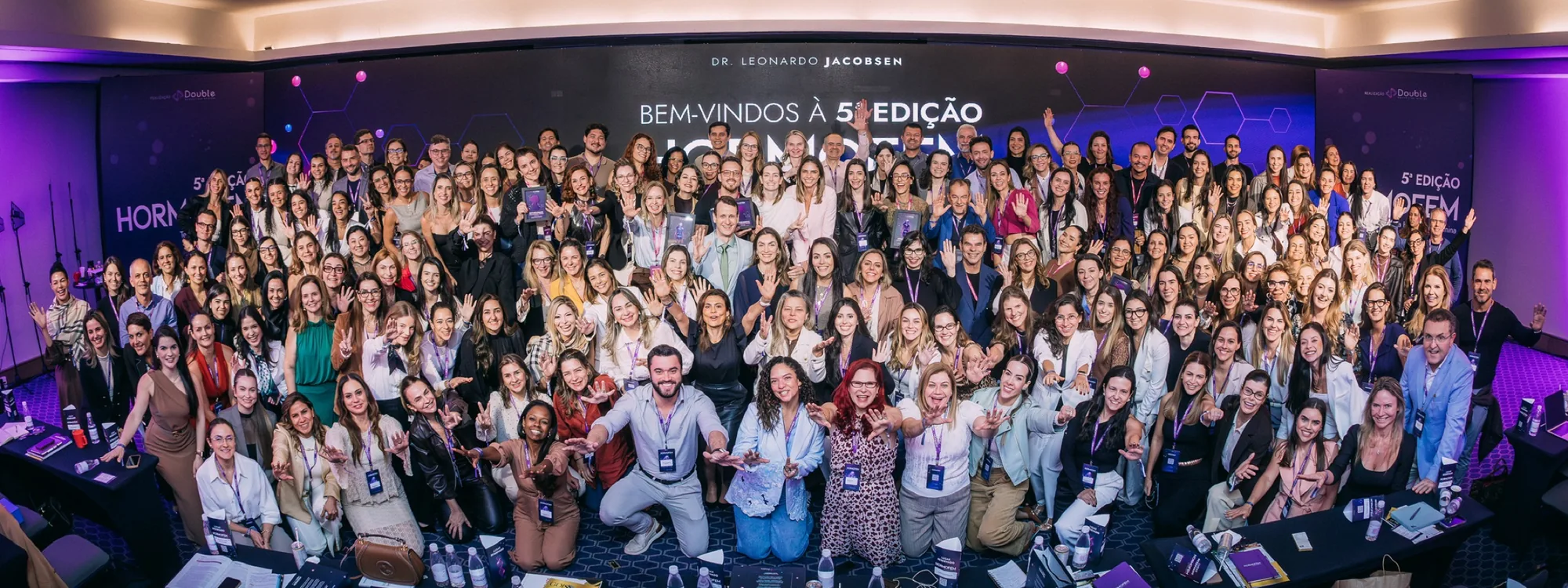 Turma da 5ª edição do Curso HORMOFEM reunida no auditório, diante do telão de boas-vindas